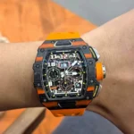 On-wrist lifestyle photo of the RM 11-03 McLaren orange chronograph, illustrating fit, scale and sporty presence.