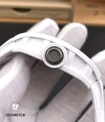 Macro close-up of the signed crown on the RM055 white ceramic, showing knurling, crown tube and precision finishing.