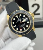 Rolex Yacht-Master 42 super clone in yellow-gold tone, shown from a 130-degree front angle with black dial and Oysterflex-style strap.