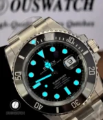 Nighttime lume display of Rolex 126610LN replica watch, showing the glow of the hands, hour markers, and bezel pip in low light