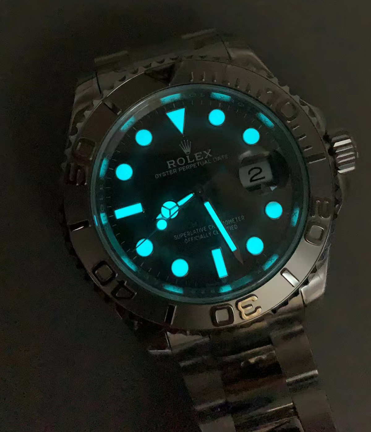 Nighttime lume display of the Rolex Yacht-Master 40 rhodium dial showing glowing hour markers and hands.